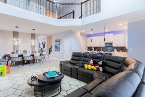ein Wohnzimmer mit einem Ledersofa und einer Küche in der Unterkunft Thematic house near DisneyGame Room in Kissimmee