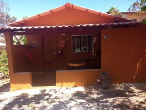 a small orange house with a table and a chair at viladasararas in Alto Paraíso de Goiás