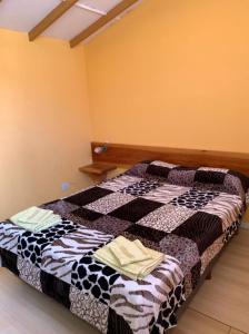 um quarto com uma cama com uma colcha preta e branca em Camping El Bolson em El Bolsón