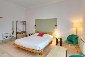1 dormitorio con 1 cama y 1 silla verde en Brit Hotel Roanne - Le Grand Hôtel, en Roanne