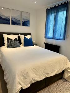 a bedroom with a large white bed with blue windows at Cocon tout confort à 25 min de Paris in Sevran