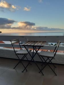 un tavolo e due sedie su un balcone con vista sull'oceano di Vistas al mar y a la montaña a Tabaiba