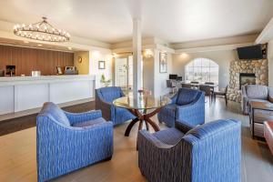 a living room with blue chairs and a table at SureStay Plus by Best Western Enterprise in Enterprise