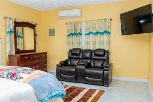 Un dormitorio con una silla de cuero negro y un espejo en Christal Sunshine, en Boca Pen
