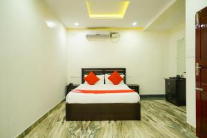 a bedroom with a bed with orange pillows at OYO Al Saj Kazhakkootam Near GreenField Stadium in Kazhakuttam