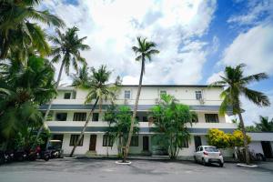 a white building with palm trees in front of it at OYO Al Saj Kazhakkootam Near GreenField Stadium in Kazhakuttam