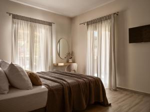 a bedroom with a bed with a blanket and two windows at Vis di Vardi Luxury Estate in Zakynthos Town