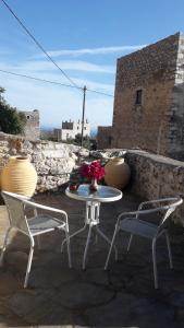 a patio with two chairs and a table with a vase of flowers at Πέτρινο σπίτι-Stone house in Koíta