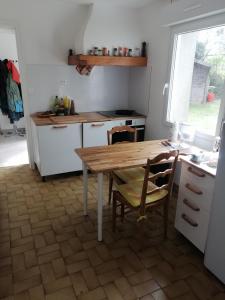 eine kleine Küche mit einem Holztisch und Stühlen in der Unterkunft Ker Loïc, Les Dunes, La Mer in Saint-Pabu