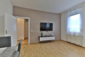 Studio Suite mit Service wie im Hotel في غوبينغِن: غرفة معيشة مع تلفزيون بشاشة مسطحة على جدار