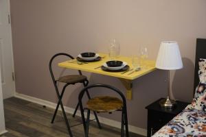 a yellow table with glasses and plates on it next to a bed at City Nest Studio #3 in London