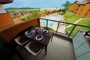 d'un balcon avec une table et une vue sur la piscine. dans l'établissement Apartamento EcoResort Carneiros, à Praia dos Carneiros