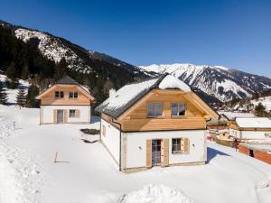 a house in the snow with mountains in the background at Chalet Norah in Donnersbachwald