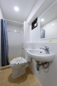 a white bathroom with a toilet and a sink at Grand Watergate Hotel in Bangkok