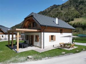 ein kleines weißes Haus mit einem Tisch und einem Sonnenschirm in der Unterkunft Haus Bente in Donnersbachwald