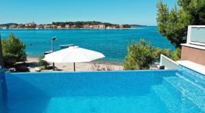 una piscina con un ombrellone e l'oceano di Pinna Nobilis MoMa level 1 a Brodarica