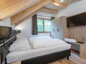 um quarto com uma cama, uma televisão e tectos em madeira em Villa Petra em Donnersbachwald