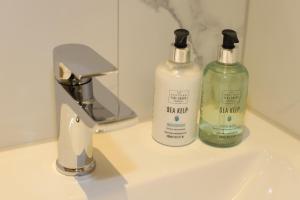 two bottles of soap dispensers sitting on a bathroom sink at Edinburgh Aparthotel in Edinburgh