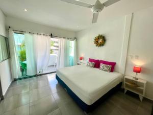 um quarto com uma cama com almofadas cor-de-rosa e uma janela em Miranda Beach em Playa del Carmen