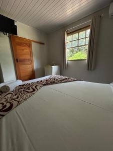 a large bed in a room with a window at Pousada Chafariz in Pirenópolis