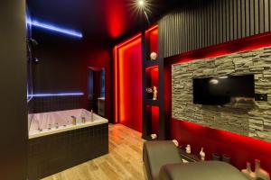 a bathroom with a tub and a television and red lights at Suite Deluxe - Jacuzzi in Melun