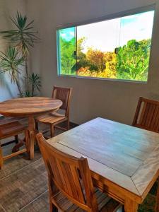 una sala da pranzo con due tavoli, sedie e una finestra di Pousada Chafariz a Pirenópolis