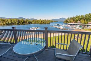a table and chairs on a deck with a view of a lake at Stunning Lake and Mountain Views, Pool, Beach, Walk to Town! in Lake Placid