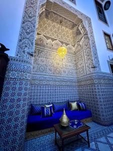 a blue couch in a room with a wall covered in tiles at Riad Dilar Fes & Spa in Fès
