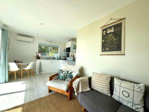 uma sala de estar com um sofá e uma cozinha em Four Huia em Oneroa