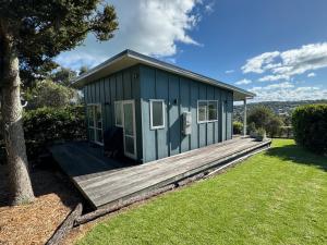 a green tiny house on a wooden deck at Four Huia in Oneroa