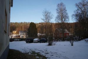 Ljungaverk的住宿－Nyrenoverad design lägenhet，两辆汽车停在房子旁边的雪盖院子