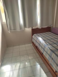 um pequeno quarto com uma cama e piso em azulejo em Claudia Apartment em Vila Velha