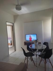 uma sala de estar com uma mesa e cadeiras e uma televisão em Claudia Apartment em Vila Velha