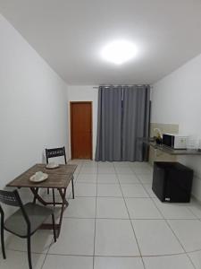 a living room with a table and chairs and a kitchen at Estúdio Charmoso no Centro de Apiaí in Apiaí