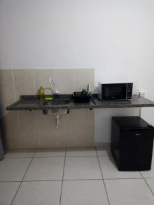 a kitchen with a counter with a microwave and a sink at Estúdio Charmoso no Centro de Apiaí in Apiaí