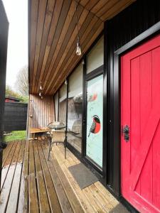 una puerta roja en una casa con un pájaro en la ventana en Hostería y Cabañas Villa Alejandra, en Máfil