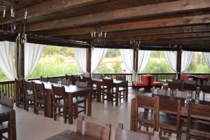 a restaurant with wooden tables and chairs and windows at Pensiunea Meridian in Corbeni
