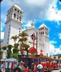 un tren delante de un gran edificio blanco en El Pacifico Hostal , Scooter, Tour & Pizza, en Juayúa