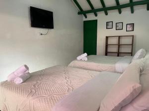 a room with three beds and a flat screen tv at Celeste Villa de Leyva in Villa de Leyva