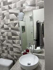 a bathroom with a sink and a toilet and a mirror at Lindo apartamento em angra dos reis in Angra dos Reis