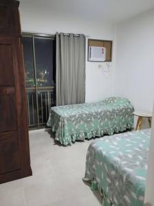 a hotel room with two beds and a window at Apartamento com varanda Reserva do Sahy in Mangaratiba +16 photos
