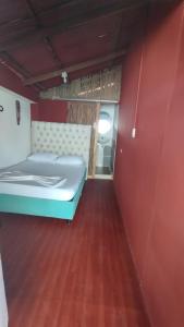 1 dormitorio con 1 cama azul en una pared roja en Cabañas Palos Locos en Barú