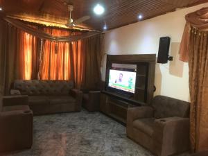 een woonkamer met een bank en een televisie bij King Makeri Guest House in Ogbojo