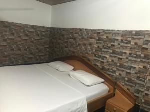 Ce lit se trouve dans une chambre dotée d'un mur en briques. dans l'établissement King Makeri Guest House, à Ogbojo