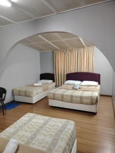 two beds in a room with an arched ceiling at Sri Juliana Chalet in Tanah Rata