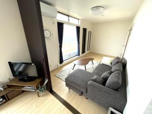 sala de estar con sofá gris y TV en RESOTIA Kakizaki en Katamachi