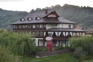 a large wooden house with a sign in front of it at Pensiunea Meridian in Corbeni