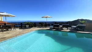 a swimming pool with chairs and umbrellas on a building at Pousada Gente Bonita Mirante in Búzios