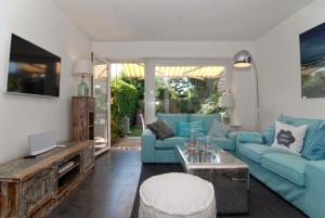 ein Wohnzimmer mit blauen Sofas und einem TV in der Unterkunft Ferienhaus Westhüs in Tinnum