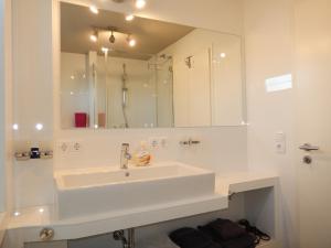 ein weißes Badezimmer mit einem Waschbecken und einem Spiegel in der Unterkunft Ferienhaus Westhüs in Tinnum